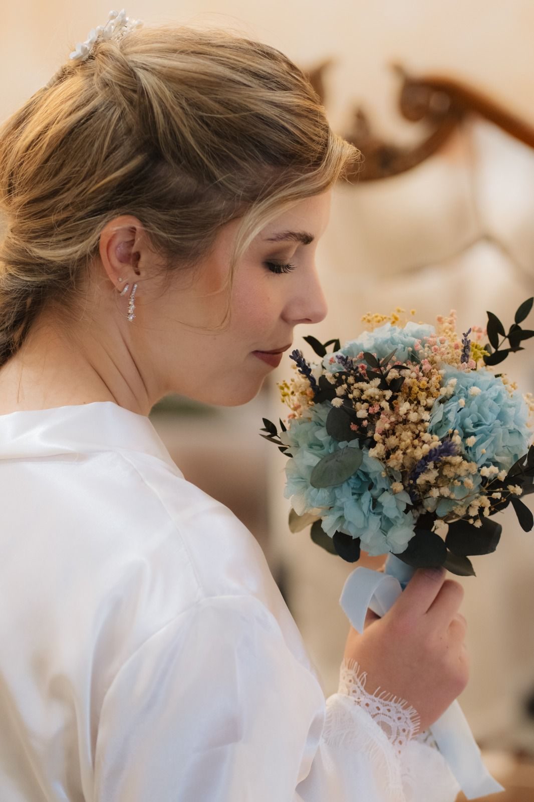 Novia de perfil con recogido y ramo de flores azules